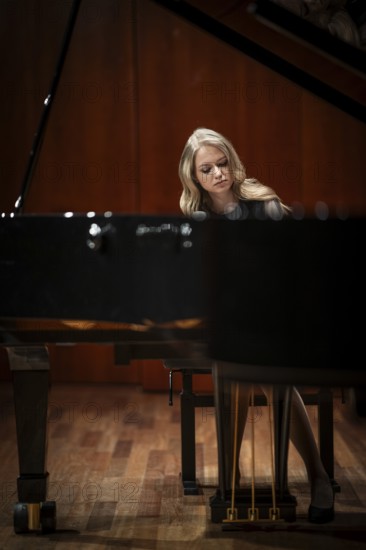 Young woman, pianist, with concentrated facial expression playing on a Steinway & Sons grand piano,