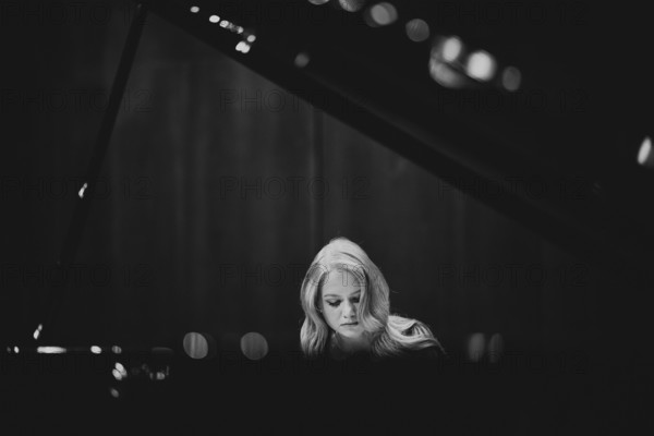Young woman, pianist, with concentrated facial expression playing on a Steinway & Sons grand piano,