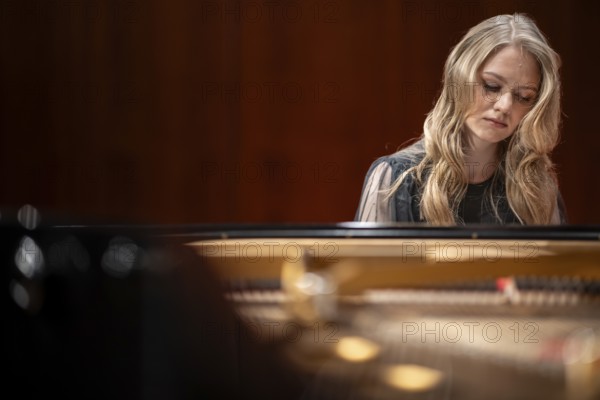 Young woman, pianist, with concentrated facial expression and closed eyes playing on a Steinway &