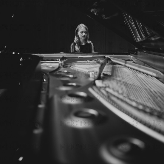 Young woman, pianist playing on an opened Steinway & Sons grand piano, black and white photo,