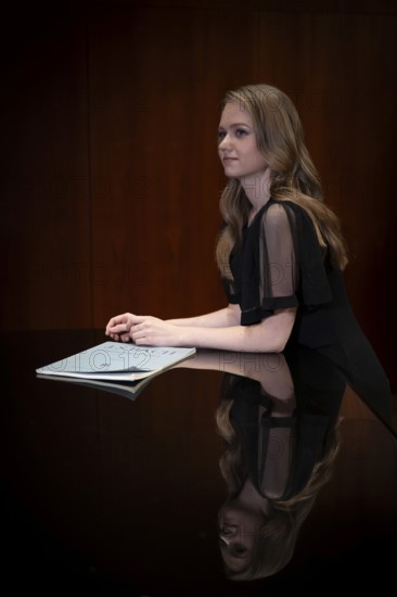 Young woman, pianist, in evening dress, with notes by Johann Sebastian Bach, supported on Steinway