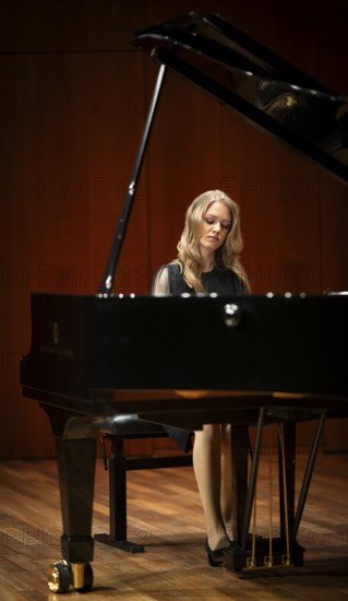 Young woman, pianist, with concentrated facial expression in a concert hall playing a Steinway &