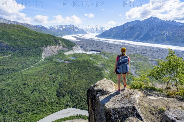 Young woman on a rocky outcrop enjoying the view, view of impressive mountain landscape with