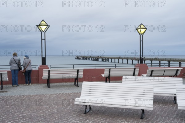 Kurplatz am spa hotel, two people from behind, pier and Baltic Sea behind, twilight, Binz, seaside