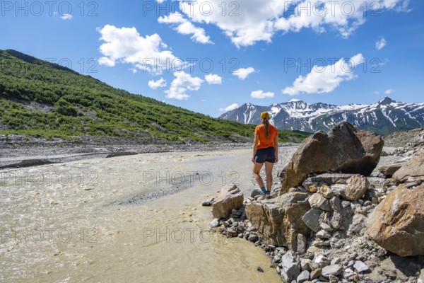 Tourist enjoying views of Miller Creek meltwater river at Castner Glacier, Delta Range, Alaska