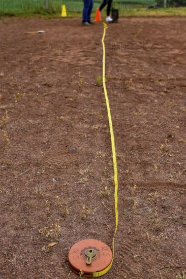 A tape measure and a sports disc lie on an ash track, marking a point in competition, Lower Saxony,