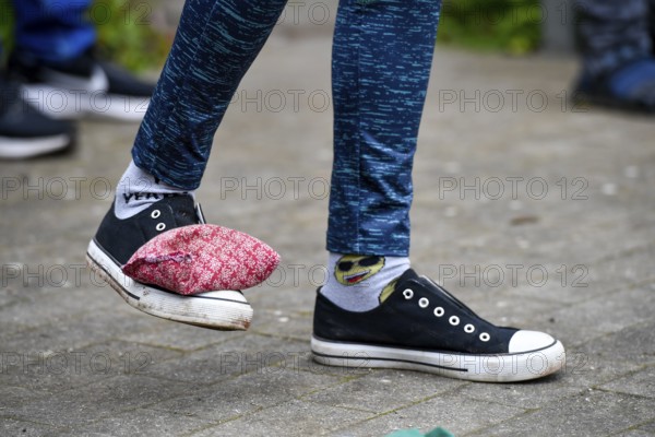 A person with patterned socks and padded shoes stands on a paved floor, Sports and Fun Olympiad