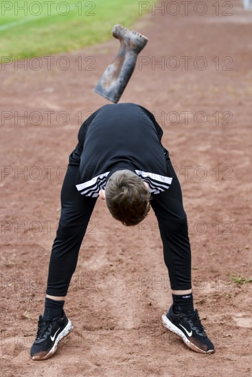 A teenager in sportswear throws a rubber boot on an ash track rubber boots long throw sports and