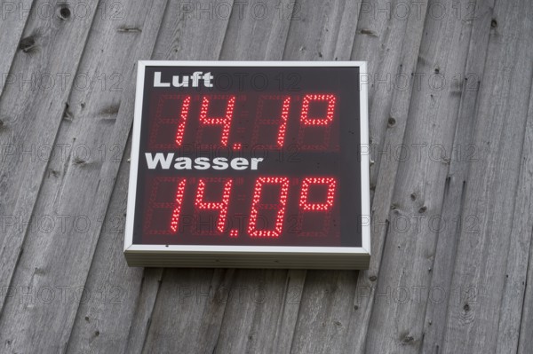 Digital thermometer for air and water hangs on a wooden wall, shows 14.1 degrees for air and 14