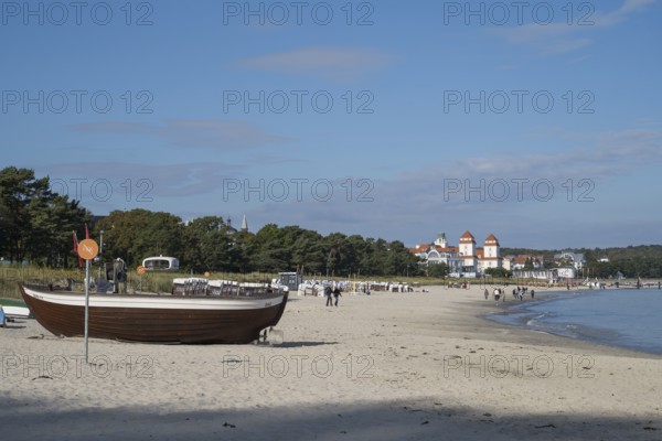 Boat with fishing flags is lying on a sandy beach, behind the spa hotel, Binz, seaside resort,