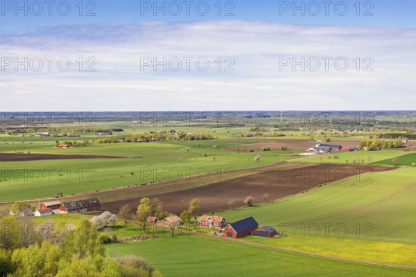 View of a cultivated plain landscape with farms and red barns a sunny spring day in th e