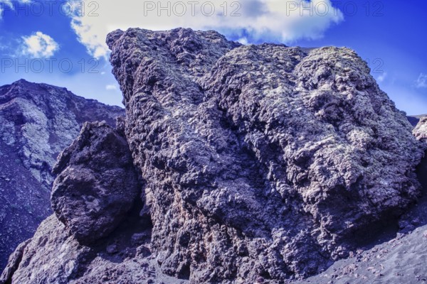 Impressive rock formation of volcanic rock rising against a blue sky, partial view of El Cuervo