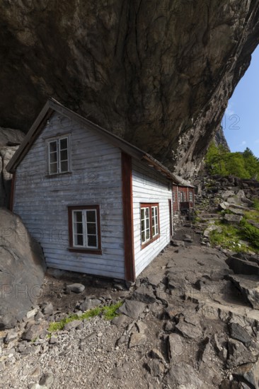 Historical wooden houses sheltered under a massive rock overhang. Summer, Helleren (Helleren),
