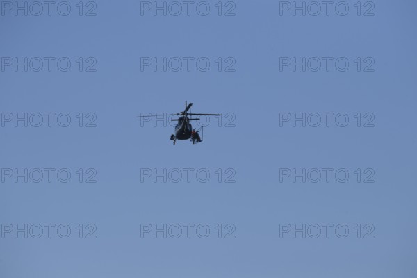 A helicopter can be seen from afar in the blue sky while it is working, Lemförde, Lower Saxony,