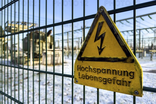 Recording of snow in winter warning sign warning high voltage danger to life on fence from behind