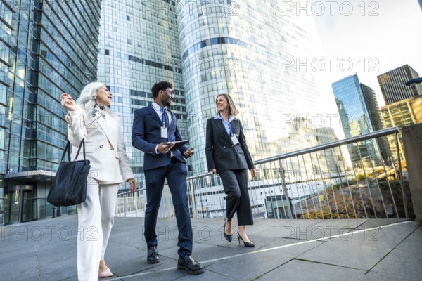 Diverse business professionals walking and discussing in a modern urban city, collaborating and