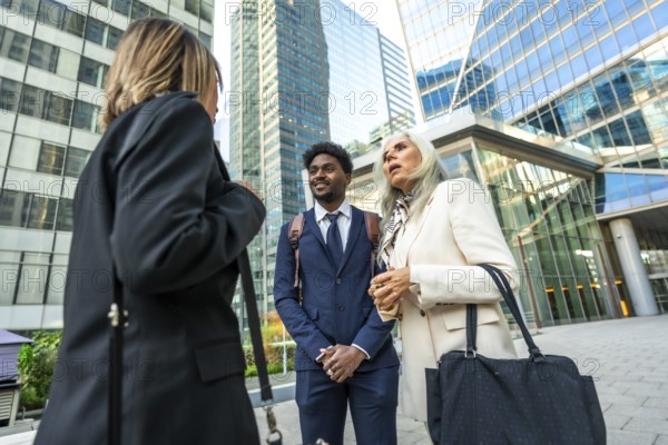 Diverse business professionals holding an informal outdoor meeting on a city street, exchanging