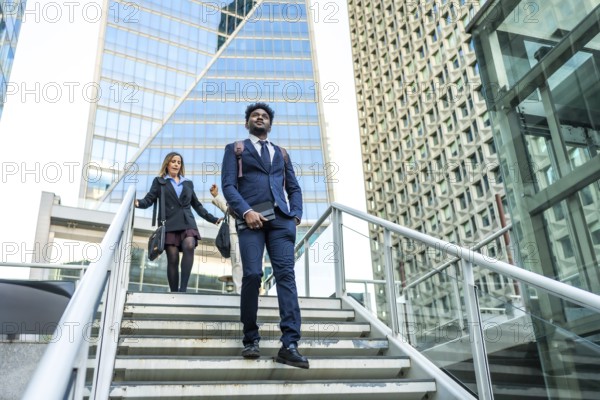 Diverse business people walking on stairs in a contemporary urban environment with tall, geometric