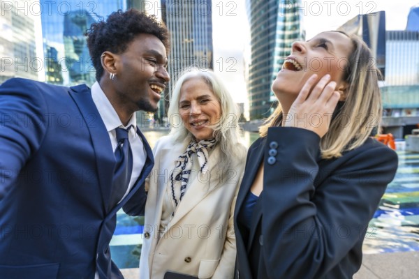 Happy business people of various ages and ethnicities are laughing together in an urban city