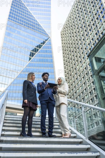 Diverse business team meeting on outdoor stairs in a downtown corporate district, collaborating