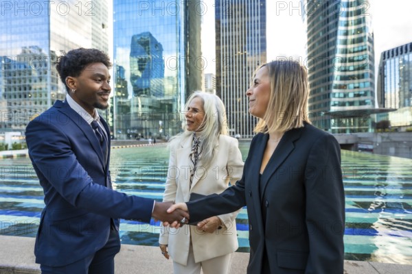 Diverse business people making a deal, shaking hands outdoors in a modern city corporate