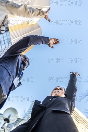 Diverse business professionals extending arms upwards, aiming for a shared objective and future