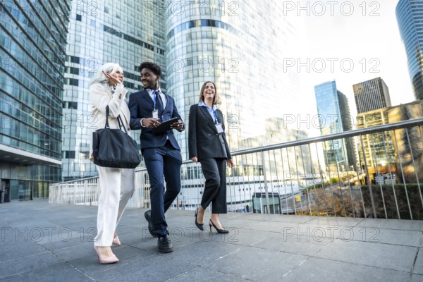 Diverse business professionals senior woman, black man, and young woman walk through a modern