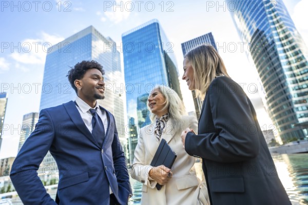 Diverse business professionals networking and discussing projects outdoors in front of modern