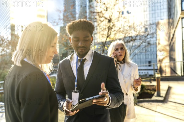 Business colleagues collaborating on an outdoor urban meeting, exchanging ideas while reviewing