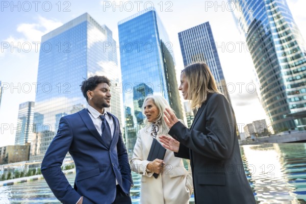 Diverse business professionals in formal attire discussing work and collaborating outdoors,