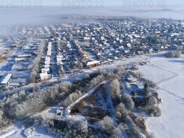 Aerial view of snowy city with fog and frost-covered fields, trees and buildings, aerial view,