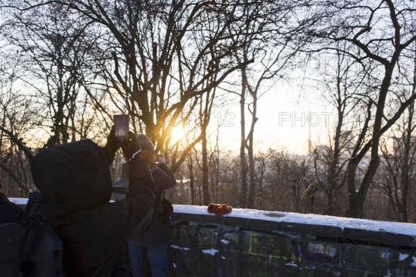 People take pictures of the Berlin TV Tower with their cell phones from Volkspark Friedrichshain on