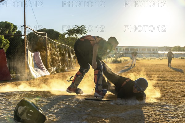 Baseball player slides into home plate at sunset, kicking up dust as catcher crouches ready for a