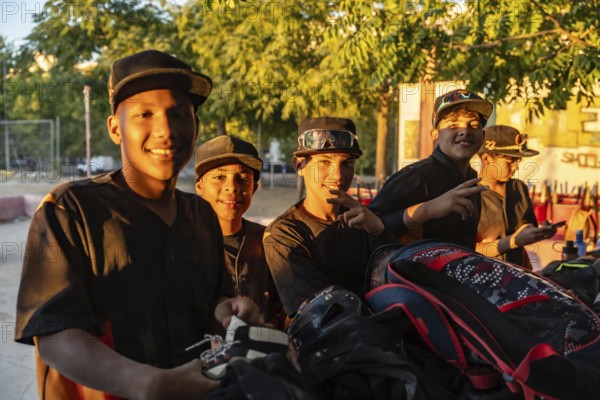 Young baseball players standing together after practice, smiling in jerseys and caps on a sunny