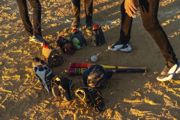Baseball players gathering on a dusty field at sunset, discussing strategy while their bats,