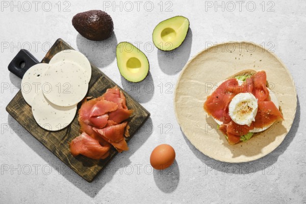 Top view of ingredients for smoked salmon sandwich with avocado, goat cheese and poached egg on a
