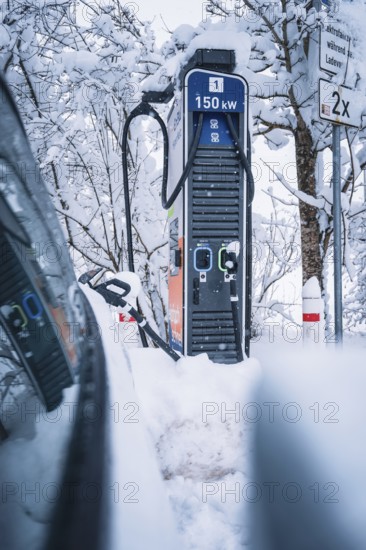 150 kW charging station in snowy surroundings next to an electric car, Tesla Model Y electric car,