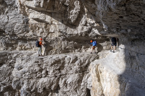 Mountaineers on an exposed rock band in the secured via ferrata Bocciere Centrale, Brenta