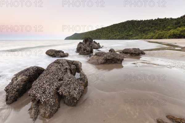 Scenic sunset view over the tropical coastline with calm ocean waves and golden light. Etty Bay