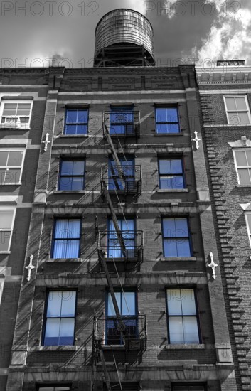 Residential building with fire escapes and wooden water tank on the roof, black and white, Downtown