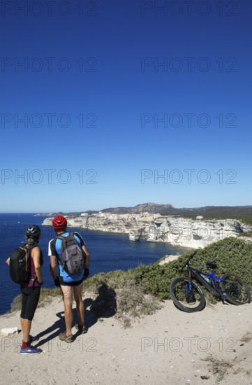 Cyclists look at the ville haute or upper town or medieval old town of Bonifacio, Corse-du-Sud