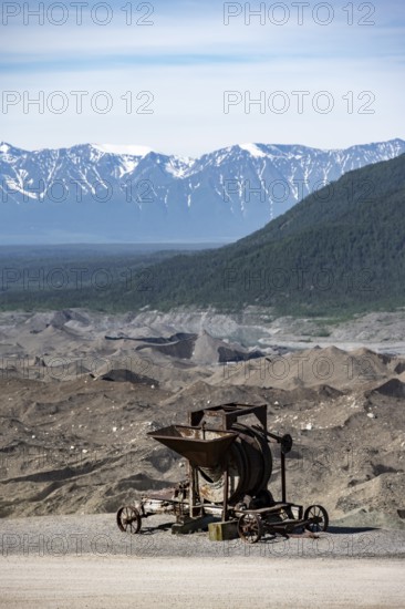 Old rusted moving mill for rock in front of mountain landscape with Kennicott Glacier, Historic