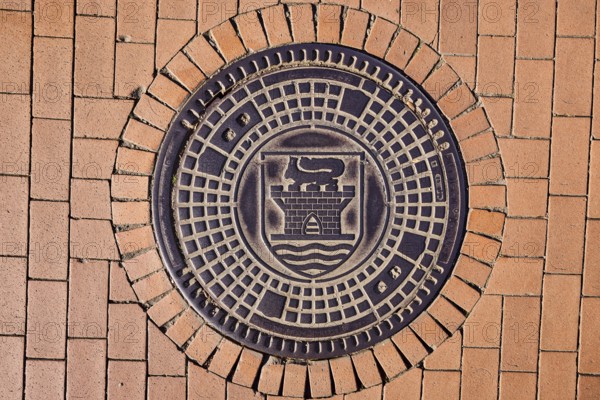 Manhole cover, city coat of arms, paving brick footpath, sunny, Eckernförde, Rendsburg-Eckernförde