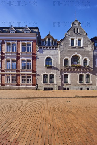 Historic residential buildings, façade with windows, gables and tail gables, paving street, blue
