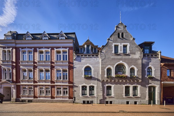 Historic residential buildings, façade with windows, gables and tail gables, paving street, blue