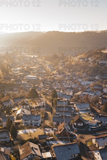 View of a village in winter at sunrise with snow-covered roofs and a golden atmosphere, Glatten,