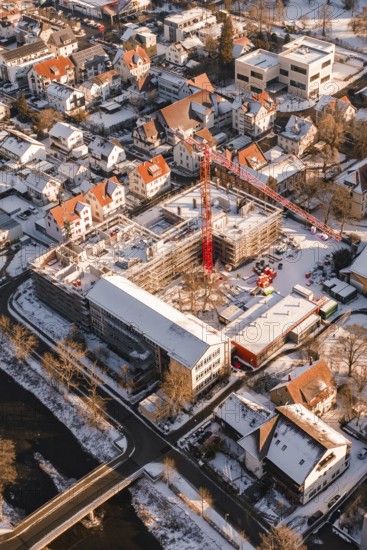 Construction site in a snowy urban area with a visible red construction crane, Zellerschule