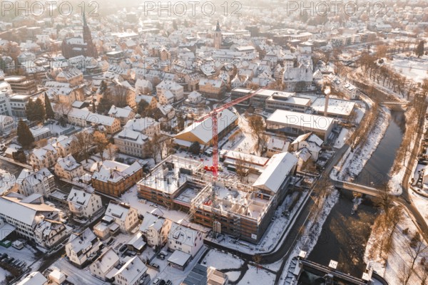 City in winter with an active construction site and visible church roof in the background,