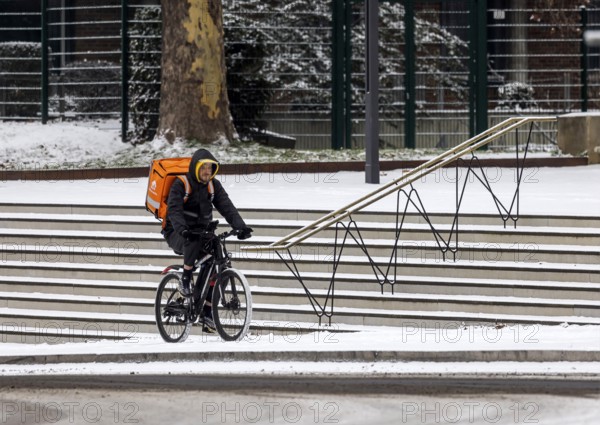 Winter in Stuttgart. There is a closed blanket of snow in the city center. Lieferando cyclists in