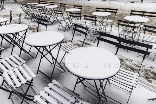 Winter in Stuttgart. Outdoor dining chairs and tables are covered with snow. Geometric structures.